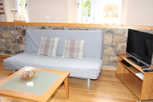 a living room with a couch and a tv at Bauernhaus in der Bachstraße in Kelberg