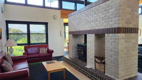 a living room with a brick fireplace with a red couch at Mary MacKillop Spirituality Centre Central Coast in Kincumber South