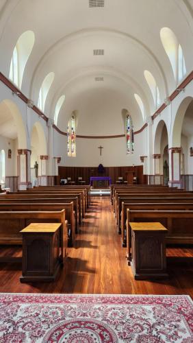 an empty church with a row of wooden pews at Mary MacKillop Spirituality Centre Central Coast in Kincumber South