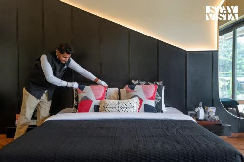 a man is making a bed in a room at The Den by Vieda - Part of StayVista in Karjat