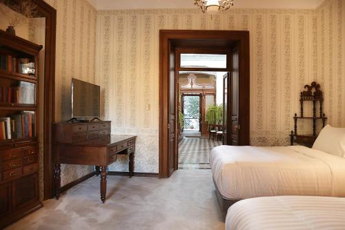 a bedroom with two beds and a desk and a television at Casa Falguera en el Centro de Guanajuato 10p in Guanajuato