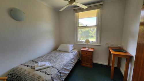 a small bedroom with a bed and a window at Mary MacKillop Spirituality Centre Central Coast in Kincumber South