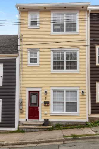 a yellow house with a red door on a street at Wood House King Bd 2 Queens Fire Pit in St. John's