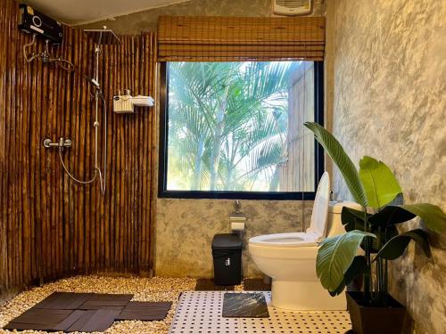 a bathroom with a toilet and a window and a plant at Bella Lunar Villa ดอยแม่สลอง in Mae Salong