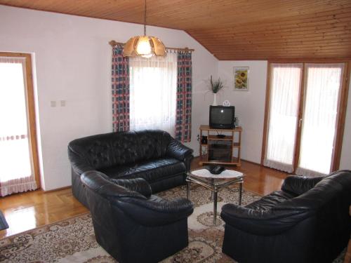 sala de estar con 2 sofás de cuero y TV en Schmidt apartment, en Balatonfenyves