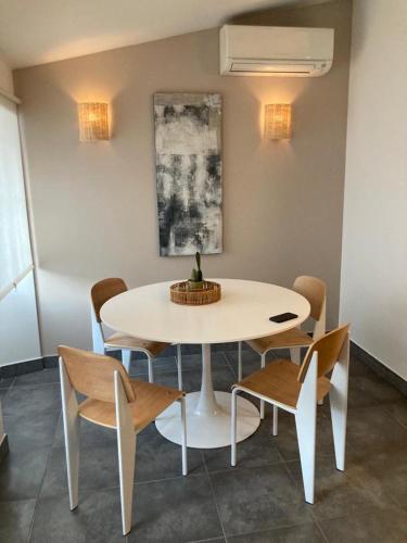 une table et des chaises dans une pièce avec une table et des chaises blanches dans l'établissement Bel appartement bord de mer, à Sainte-Maxime