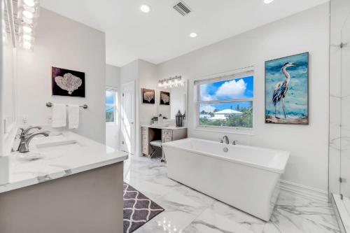 een witte badkamer met een groot bad en een wastafel bij Paradise on Pine in Anna Maria