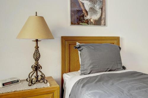 a bedroom with a bed and a lamp on a night stand at Peaceful creek view from the deck! Walk to Shuttle in Vail