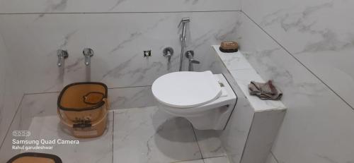 a white bathroom with a toilet and a sink at Gurukrupa Yatri Niwas in Garudeshwar