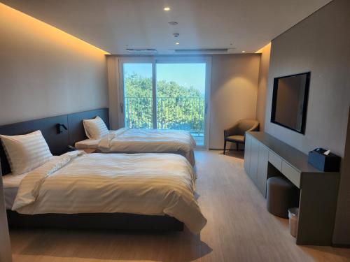 a hotel room with two beds and a television at PANAQ operated by SONO in Yeongdeok