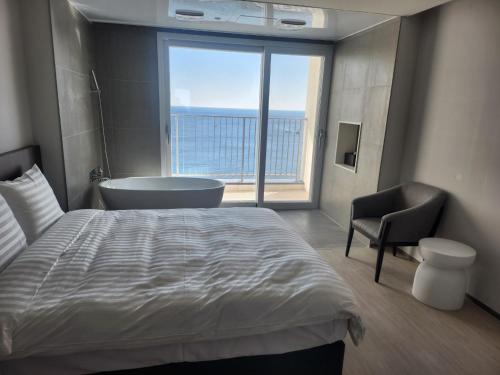 a bedroom with a bed and a bath tub and a window at PANAQ operated by SONO in Yeongdeok