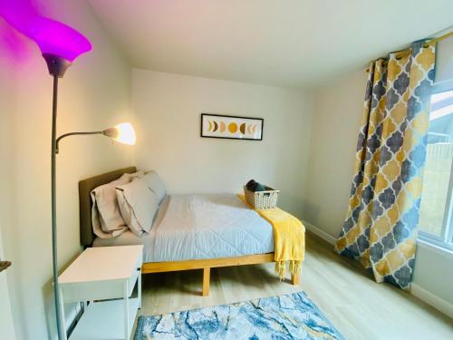 a small bedroom with a bed and a lamp at Cheerful 4 bed, 2 bath with pool near Disneyland in Placentia
