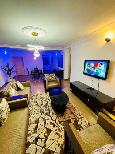 a living room with couches and a flat screen tv at Maitama Apartment in Abuja