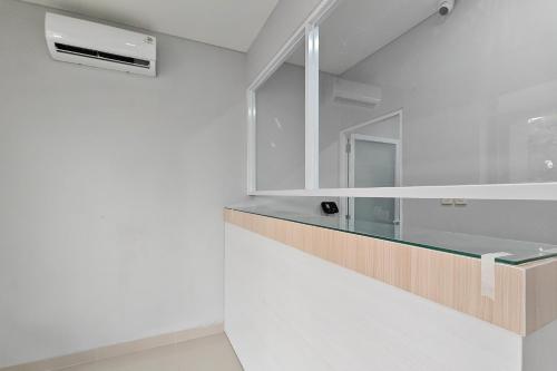 a white kitchen with a glass counter and a sink at Urbanview Green Lake Sunter Residence in Jakarta