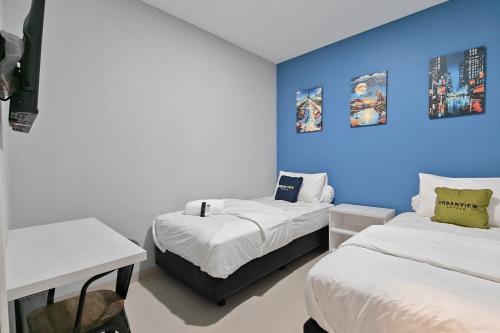a bedroom with two beds and a blue wall at Urbanview Green Lake Sunter Residence in Jakarta