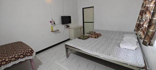 a small bedroom with a bed and a mirror at Kulswami Cottage Alibag in Alibaug