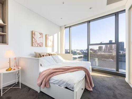 a white bedroom with a bed and a large window at Riverfront 2 Bedroom Apt in Brisbane City with Parking in Brisbane