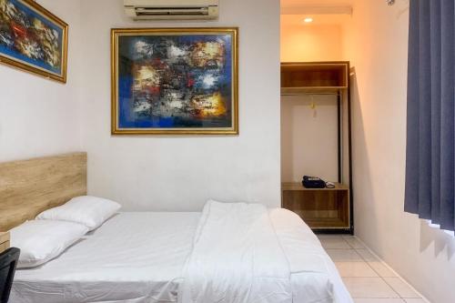 a bedroom with a white bed and a painting on the wall at Urbanview Hotel Rimadi Slipi in Jakarta