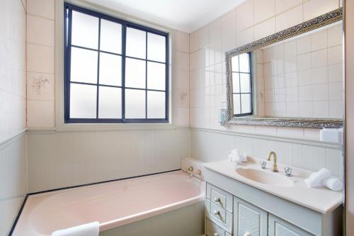 a white bathroom with a tub and a sink and a bath tubermottermottermott at Three Bedroom Sweet Retreat in Coburg in Melbourne