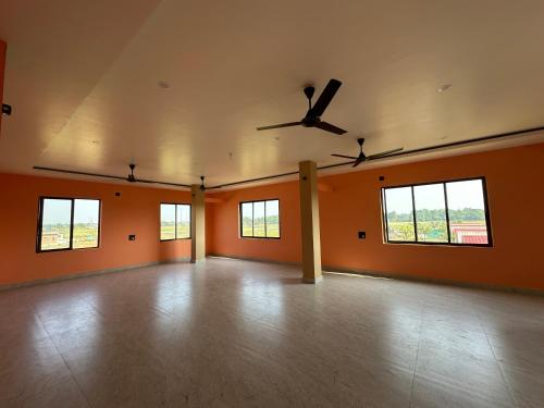 an empty room with a ceiling fan and windows at Alpine Resort in Sivasagar
