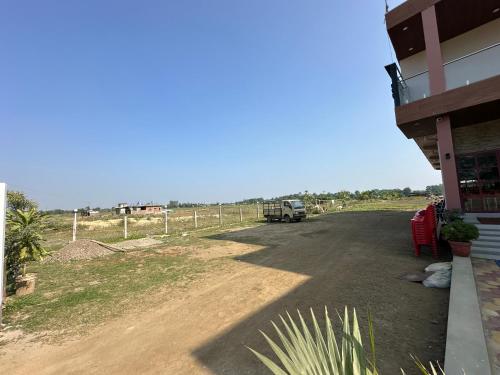 a dirt road next to a building with a truck parked at Alpine Resort in Sivasagar
