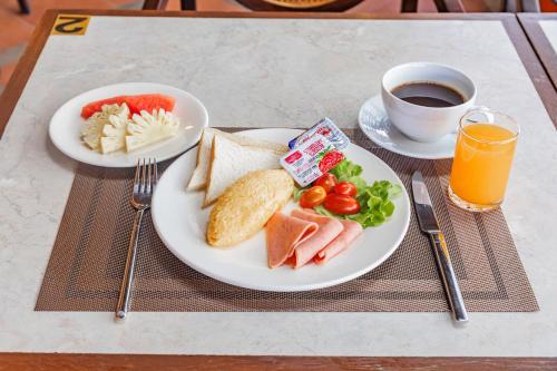 a table with two plates of breakfast food and a cup of coffee at Rattana Karon Beach Hotel in Karon Beach