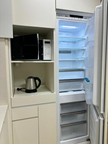 a refrigerator with its door open with a tea pot in it at The Hide City in Jeju