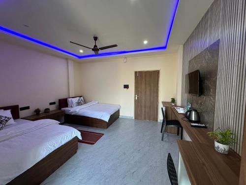 a hotel room with two beds and a television at Alpine Resort in Sivasagar