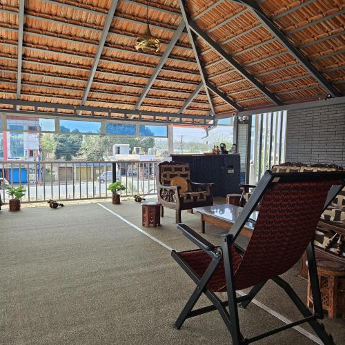 a patio with two chairs and a table and a balcony at MysticGreens Guest House! in Kushālnagar