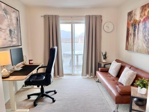 a living room with a couch and a desk with a computer at The Joshua Tree House in Joshua Tree