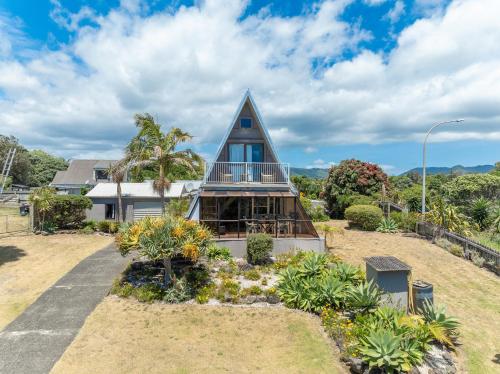 a house with a gambrel roof with a balcony at Ahiparadise - Ahipara Holiday Home in Ahipara