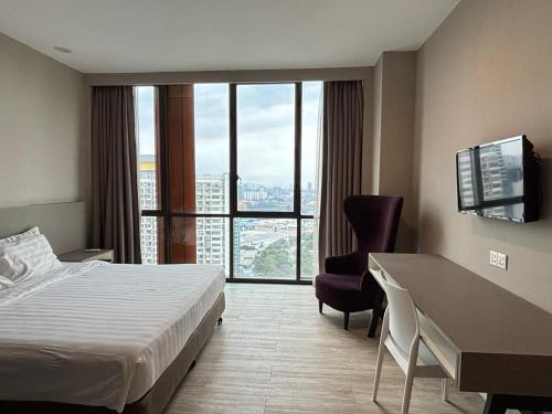 a hotel room with a bed and a desk and a window at QQ Empire Damansara hotel room in Petaling Jaya