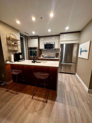 a kitchen with a refrigerator and two bar stools at Century Park Condo Oasis in Edmonton