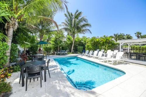 a swimming pool with chairs and a table next to a pool at Blissful Bay at Bayside Bungalow in Anna Maria