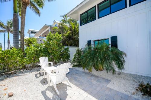 two white chairs and a table in front of a building at Blissful Bay at Bayside Bungalow in Anna Maria