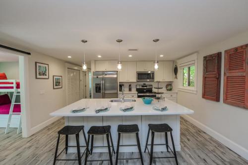 a kitchen with a large island with three bar stools at Blissful Bay at Bayside Bungalow in Anna Maria