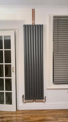 a radiator on a wall next to two windows at Number 14 in Ipswich