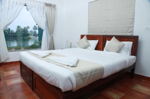 a bedroom with a large bed with a window at Arayaal Serviced Villa in Champakulam