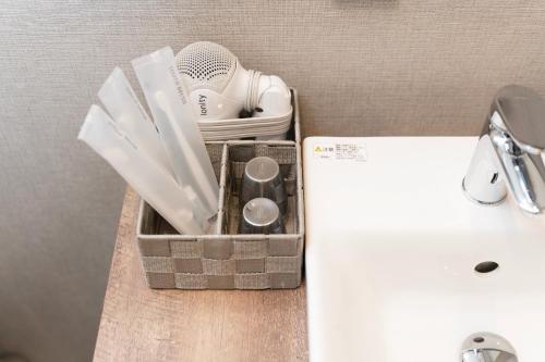 a basket with utensils on a counter next to a sink at e-stay ebisu in Osaka