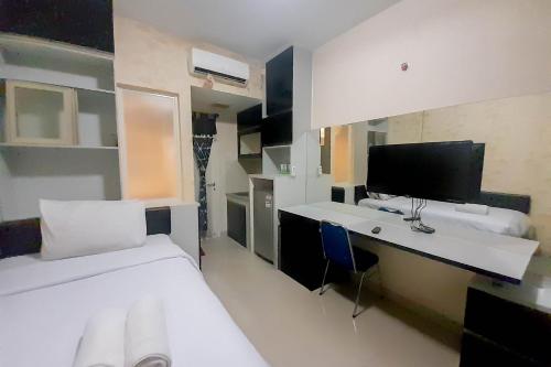um quarto com uma cama e uma escrivaninha com um computador em Comfort and Cozy Studio Student Castle Yogyakarta Apartment By Travelio em Seturan