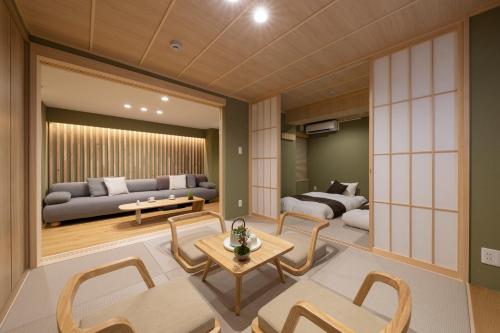 a living room with a couch and a table and chairs at Shirakabanoyado-KI NO NOKI, 白樺の宿-木の軒, SELF CHECK-IN in Osaka