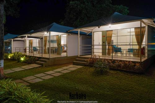 a house at night with chairs in front of it at White Feather Resort Kauncha in Silvassa