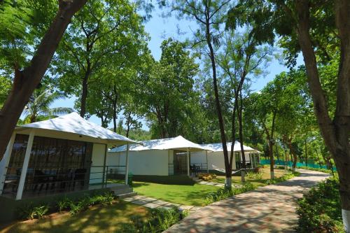 a row of tents in a park with trees at White Feather Resort Kauncha in Silvassa