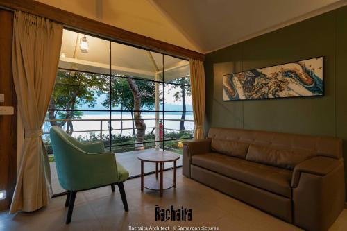 a living room with a couch and a table and a window at White Feather Resort Kauncha in Silvassa