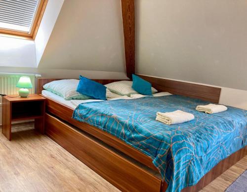 a bedroom with a bed with blue sheets and blue pillows at Penzion a restaurace Myslivna Kolence - Třeboňsko in Třeboň