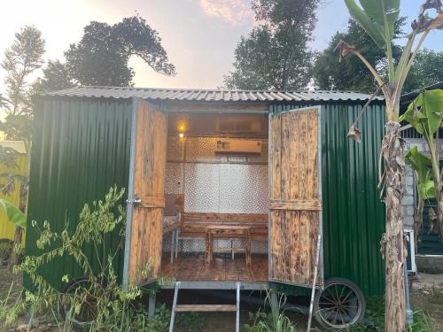 a green and wooden house with a table in it at Vuglamping in Hue