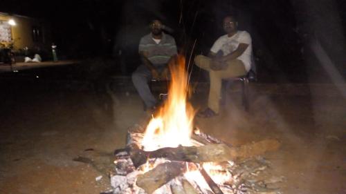 two men are sitting around a fire at night at Spinson Home Stay in Madikeri