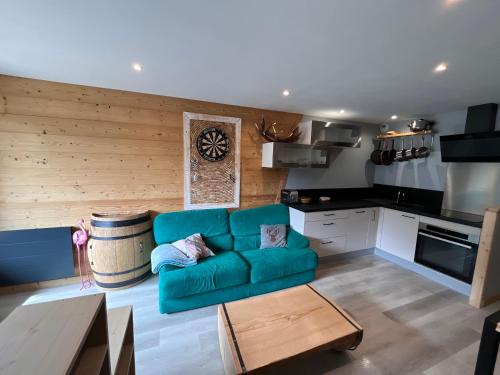 a living room with a blue couch and a kitchen at Le studio de mimi in Le Grand-Bornand