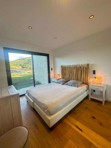 une chambre avec un grand lit et une grande fenêtre dans l'établissement Sublime villa vue mer pieds dans l'eau, à Monticello
