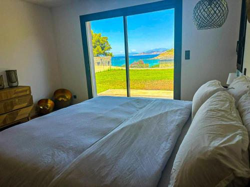 a bedroom with a large bed with a large window at Sublime villa vue mer pieds dans l'eau in Monticello